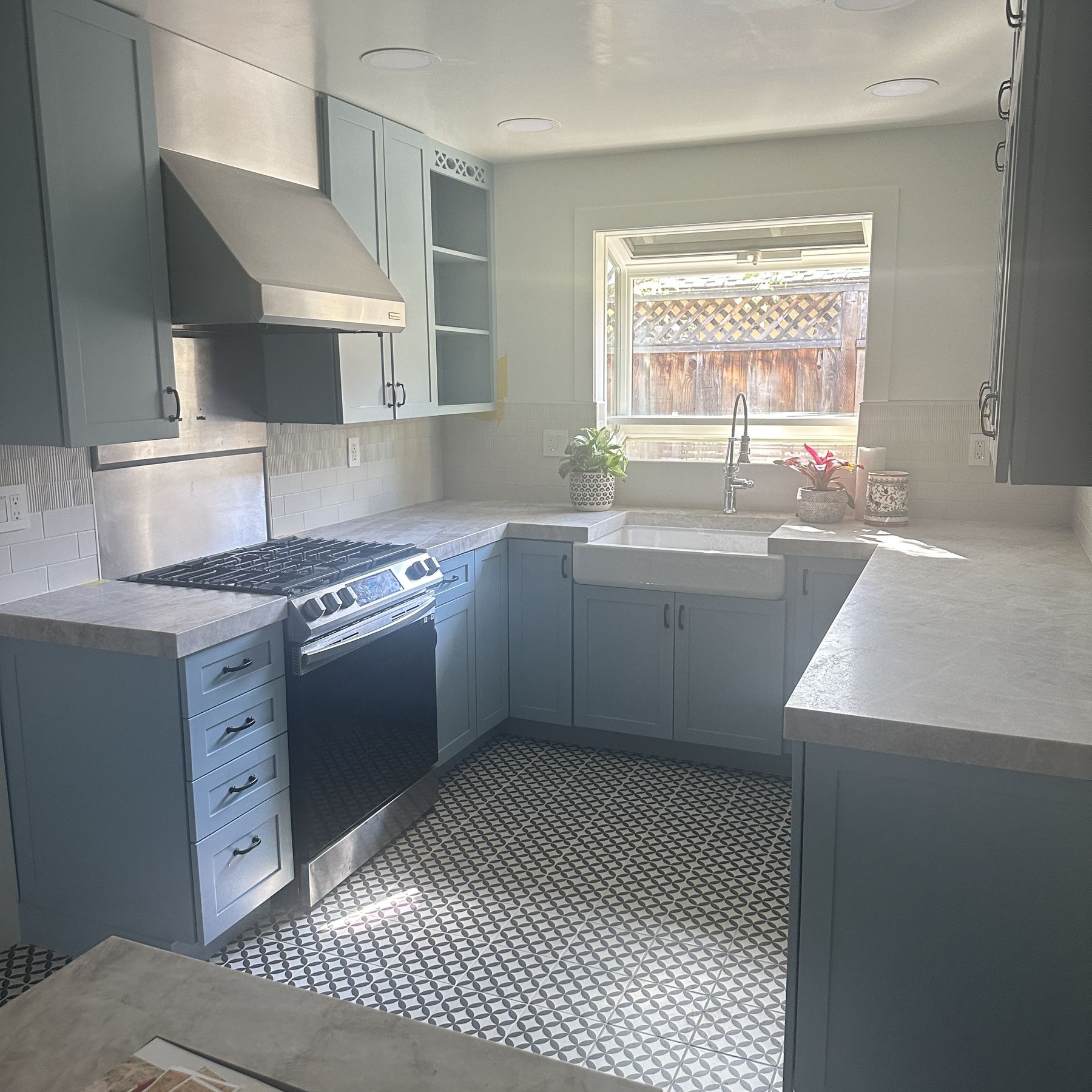 Range, hood, and open shelving on the left side of the kitchen