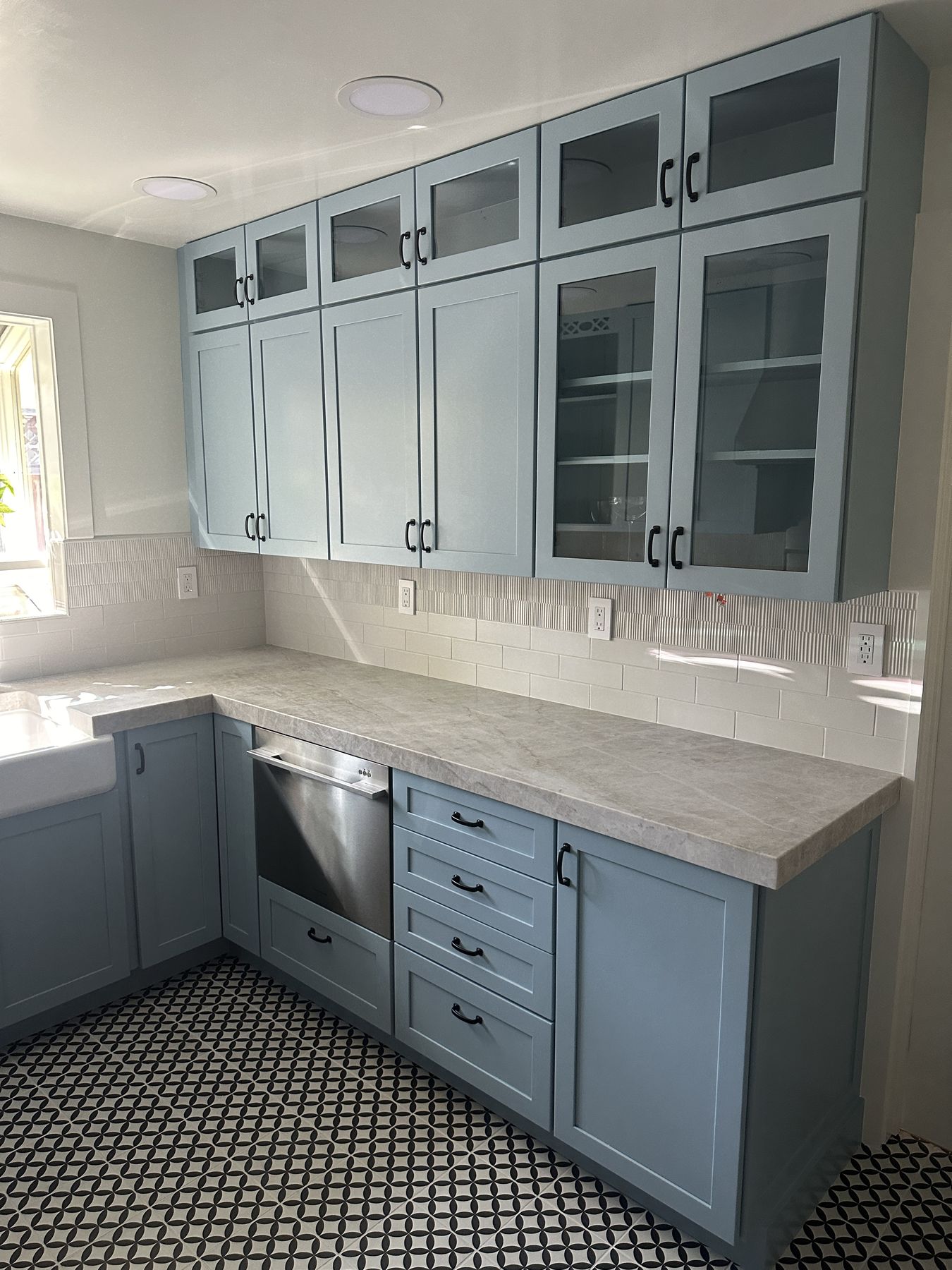 Glass-front upper cabinets stacked to the ceiling over stone counters
